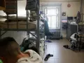 Wnętrze celi, areszt śledczy. Dwie osoby na łóżkach piętrowych, okno z kratami, telewizor.