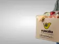Mężczyzna niesie kartonowe pudełko z produktami spożywczymi, które jest częścią elektronicznej paczki żywnościowej.