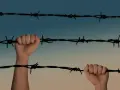 Dwie dłonie zaciskają się na drutach kolczastych, symbolizując walkę o darowanie lub złagodzenie kary.