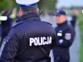 Policjanci w mundurach, jeden z napisem "POLICJA" na plecach, gotowi do akcji. Czy to kontrola osobista, czy przeszukanie?