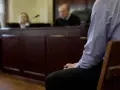 Osoba siedzi w ławie sądowej, czekając na decyzję w sprawie zgodnej z art. 37a. Sąd obraduje.