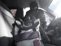 Złodziej w masce sięga po torbę w samochodzie. To jeden z rodzajów kradzieży, które mogą spotkać każdego.
