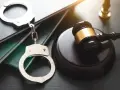 Kajdanki i młotek sędziowski na tle ksiąg prawnych. Symbol sprawiedliwości i egzekwowania prawa, zgodny z kodeksem wykonawczym.