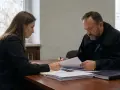 Adwokat w todze i kobieta analizują dokumenty. Stawiennictwo nieobowiązkowe na rozprawie karnej wymaga przygotowania.