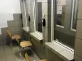 Pokój widzeń w zakładzie karnym półotwartym. Proste krzesła i telefony czekają na rozmowy.