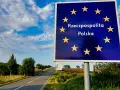 Granica Polski. Znak z gwiazdami Unii Europejskiej i napisem "Rzeczpospolita Polska". Droga prowadzi w głąb kraju, gdzie można złożyć wniosek o uchylenie zakazu opuszczania kraju.