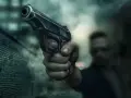 Dłoń trzyma pistolet, gotowa do strzału. Scena sugeruje sytuację z art. 64 par. 2 kk, gdzie groźba użycia broni może być kluczowa.