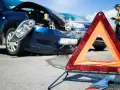 Wypadek drogowy, uszkodzone samochody, trójkąt ostrzegawczy i policjant spisujący notatki. Sprawcy grozi kara grzywny z art. 177 k.k.