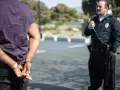 Policja doprowadzenie do zakładu karnego. Mężczyzna w kajdankach, obok funkcjonariusz.
