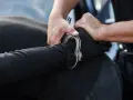 Ręce funkcjonariusza ABW zakładają kajdanki na nadgarstek zatrzymanego.