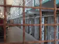 Korytarz więzienny z celami, schodami spiralnymi i kratami. To miejsce, gdzie uczysz się, jak przetrwać w więzieniu.