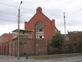 Ceglane mury, wieżyczka strażnicza i wielkie okno z kratami. To więzienie inaczej, z widokiem na ulicę i drzewa.