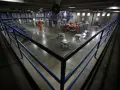 Wnętrze więzienia w USA. Więźniowie w pomarańczowych strojach poruszają się po betonowym dziedzińcu, gdzie znajdują się stoły i łóżka.