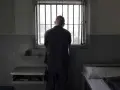 Samotny więzień patrzy przez kraty okna. To obraz odzwierciedlający cele wykonywania kary pozbawienia wolności: izolację i refleksję.