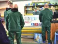 Strażnicy więzienni w zielonych uniformach robią zakupy w więziennej kantynie.