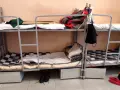 Tak wygląda dzień w areszcie śledczym: piętrowe łóżka, koce, poduszki i buty na podłodze.