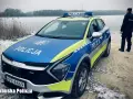 Policyjna lodówka stoi nad zamarzniętym jeziorem. Policjant w mundurze obserwuje okolicę.