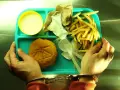 Posiłek w więzieniu: ręce w kajdankach trzymają tacę z hamburgerem, frytkami i napojem.