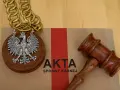 Na brązowej teczce z napisem "AKTA SPRAWY KARNEJ" leży drewniany młotek sędziowski i medalion z orłem RP.