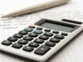 Kalkulator i długopis na kartce w kratkę, symbolizujące analizę finansową i potencjalne najczęstsze przestępstwa skarbowe.