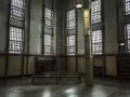 Wnętrze zakładu karnego z kratami w oknach i ławkami. Dowiedz się, jak uzyskać pozwolenie na widzenie w zakładzie karnym.