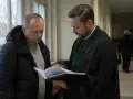 Prawnik w todze pokazuje klientowi dokumenty. Rozmawiają o wniosku o naprawienie szkody kpk.