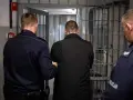 Dwóch policjantów eskortuje mężczyznę do celi. To początek jego pobytu w areszcie tymczasowym.