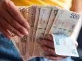 Dłonie trzymają plik banknotów 200 zł i 50 zł. Jak egzekwować obowiązek naprawienia szkody, gdy sprawca nie chce zapłacić?