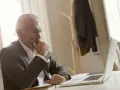 Biznesmen w garniturze zamyślony nad laptopem, przygotowuje się do wszczęcia śledztwa.