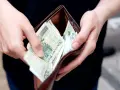 Dłonie wkładają polskie banknoty do portfela. Może to symbolizować rekompensatę za nękanie, która wreszcie trafia do poszkodowanego.