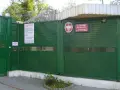 Zielona brama z drutem kolczastym i znakiem "Schronisko dla Nieletnich w Dominowie". To miejsce, gdzie młodzież potrzebuje wsparcia, a nie kary.