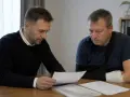 Mężczyzna z ręką w temblaku i bandażu analizuje dokumenty. Prawdopodobnie przygotowuje wniosek o zadośćuczynienie.