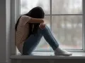Dziewczyna siedzi skulona przy oknie, pogrążona w smutku. Obraz symbolizuje traumę po przestępstwach na tle seksualnym.