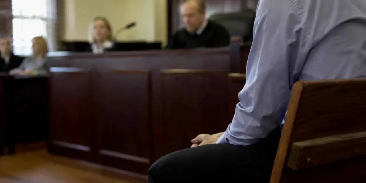 Osoba siedzi w ławie sądowej, czekając na decyzję w sprawie zgodnej z art. 37a. Sąd obraduje.
