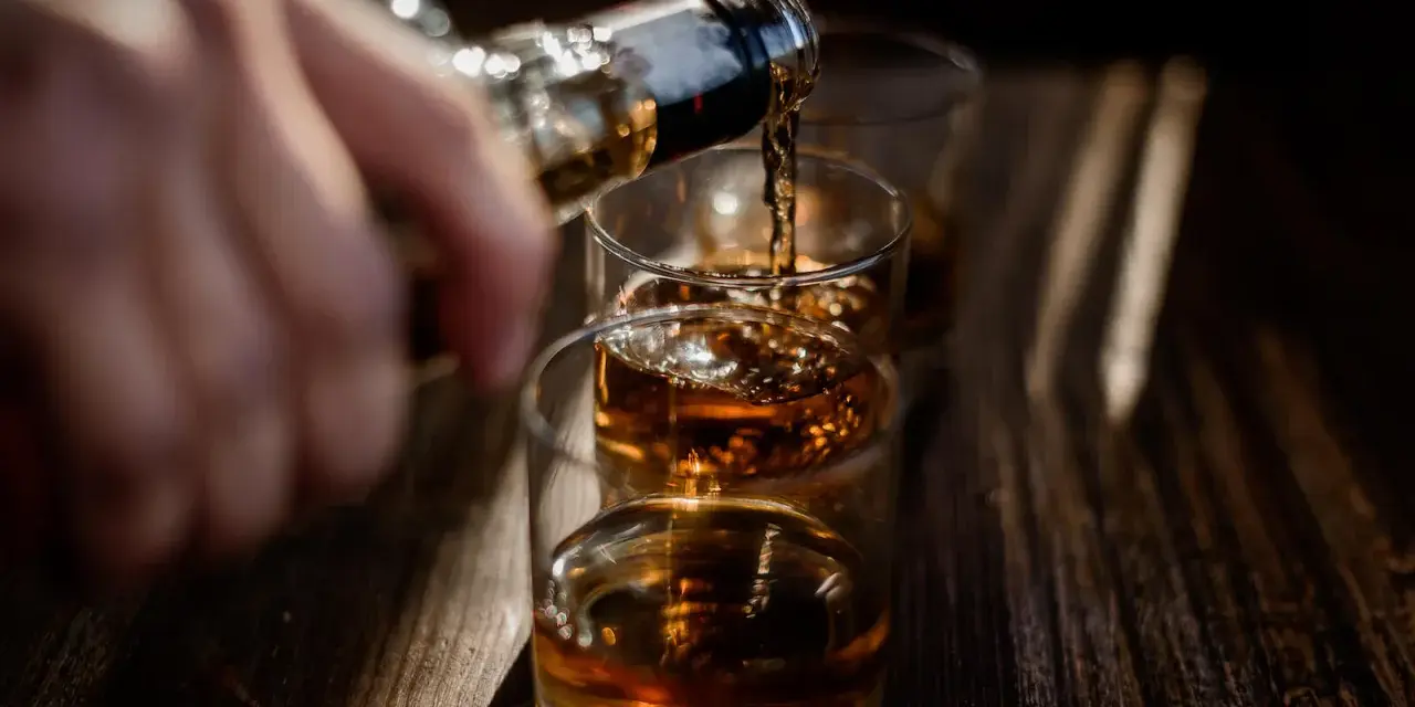 Nalewanie alkoholu do szklanek. Ta scena może symbolizować sprawę w sądzie za picie alkoholu przez nieletnich.