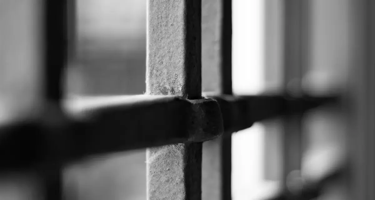 Wniosek o wstrzymanie wykonania zastępczej kary pozbawienia wolności wzór. Metalowe kraty, symbolizujące uwięzienie, na tle rozmytego światła.