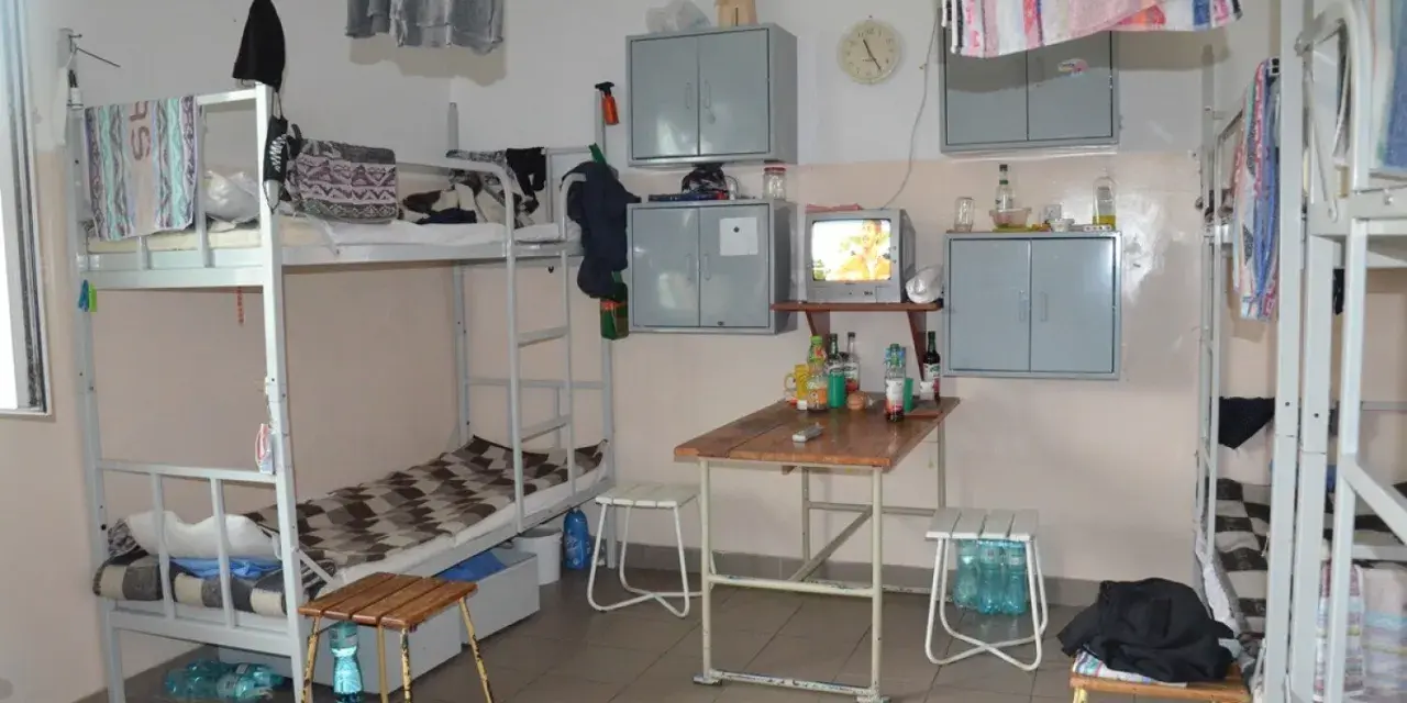 Wnętrze przypomina **zakład karny cela** z łóżkami piętrowymi, stołem, telewizorem i szafkami.