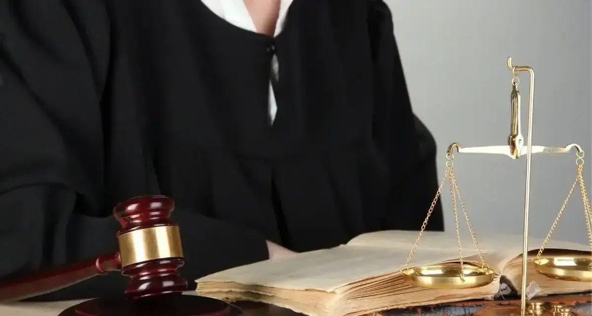 Sędzia w todze, młotek, waga sprawiedliwości i księgi symbolizują prawo i nadzwyczajne środki zaskarżenia.