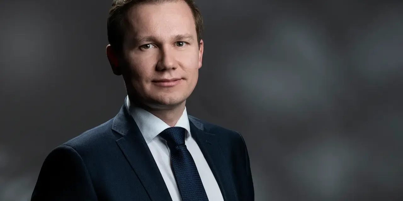 Mężczyzna w garniturze, gotowy do przesłuchania w charakterze świadka.