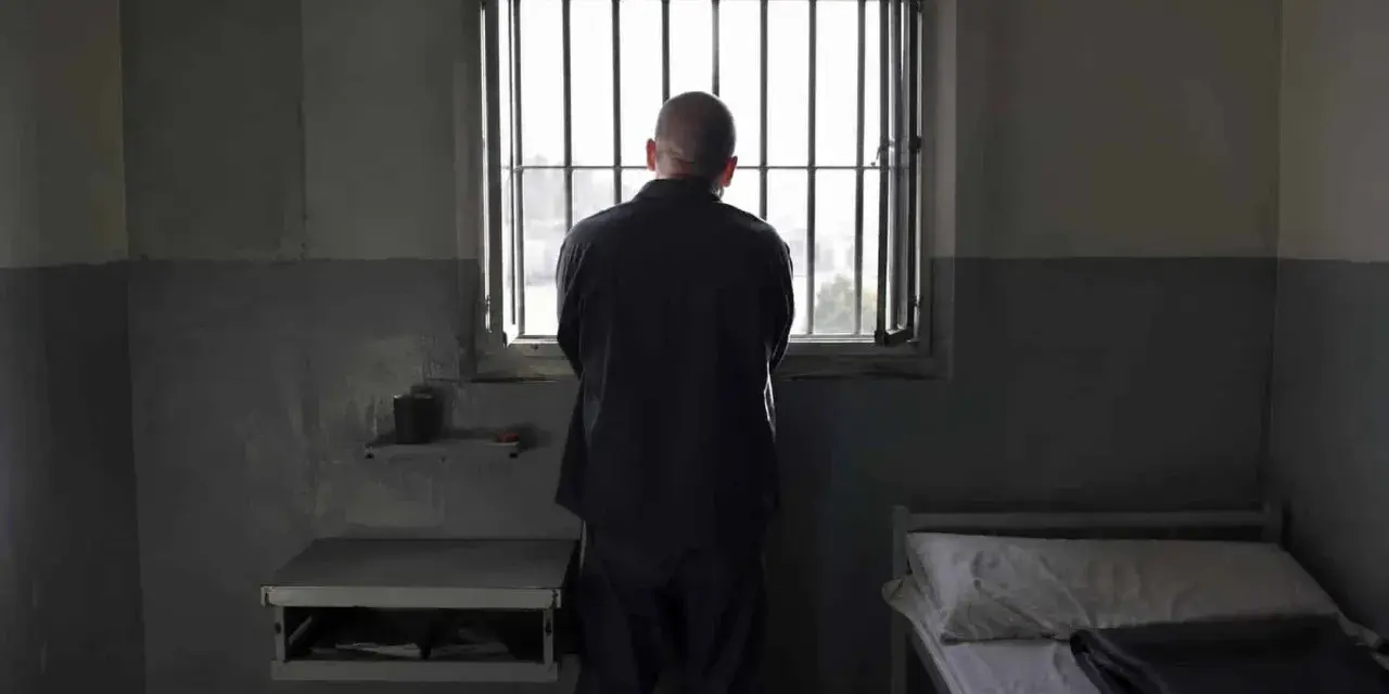 Samotny więzień patrzy przez kraty okna. To obraz odzwierciedlający cele wykonywania kary pozbawienia wolności: izolację i refleksję.