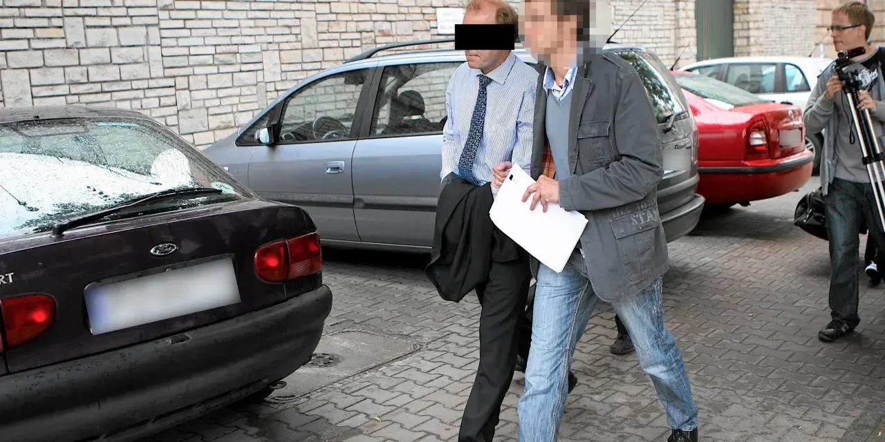 Dwóch mężczyzn, jeden w garniturze, drugi w kurtce i jeansach, idzie obok samochodów. Czy to występek, co to za sytuacja?