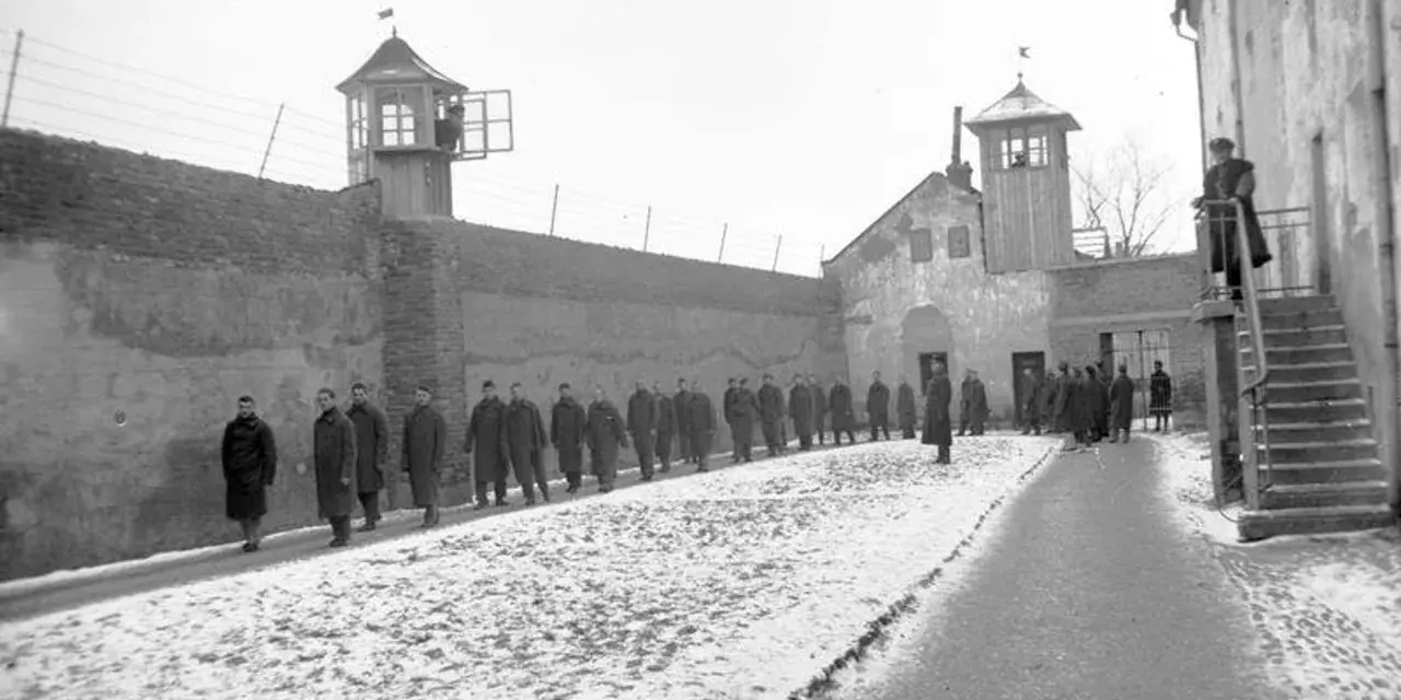 Więźniowie w mroźny dzień na dziedzińcu jednego z najcięższych więzień w Polsce. Strażnicy obserwują z wieżyczek.