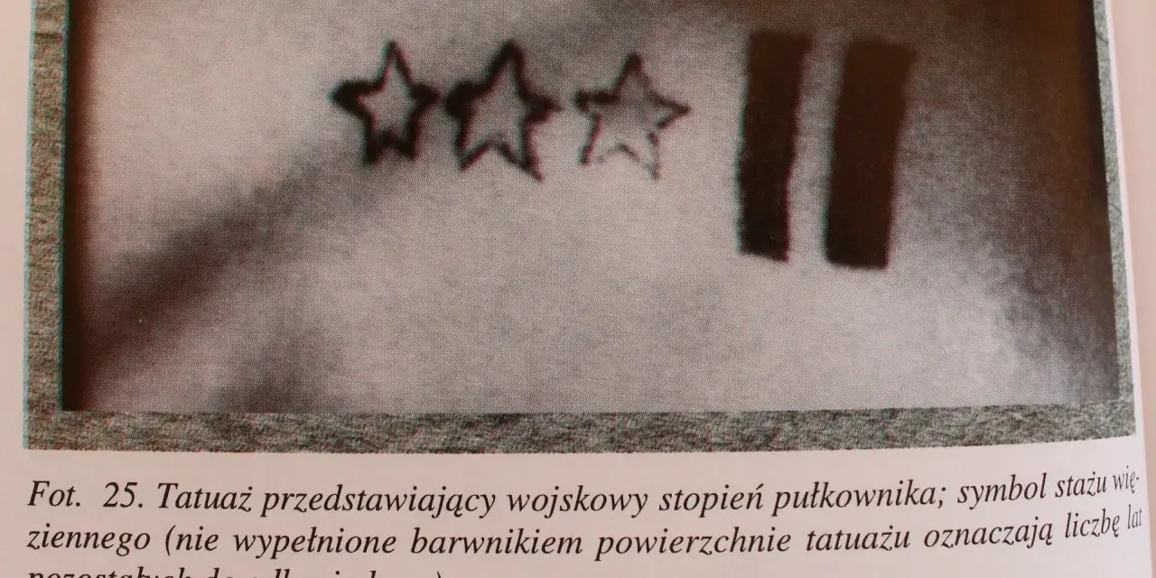 Trzy gwiazdy i dwie pionowe kreski – tatuaże więzienne, symbolizujące stopień wojskowy i czas pozostały do odbycia kary.