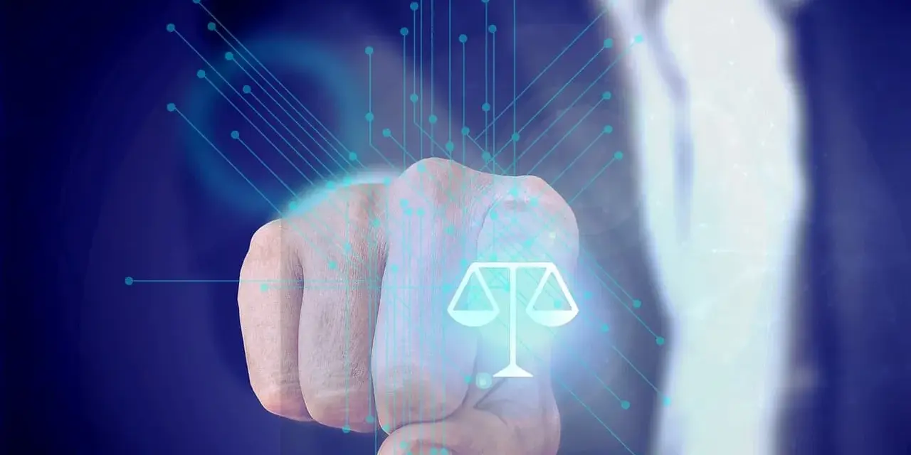 Dłoń wskazuje na symbol wagi sprawiedliwości, otoczony cyfrowymi połączeniami. Może to symbolizować sprawiedliwość w erze cyfrowej, np. w kontekście artykułu 119 kodeksu karnego.