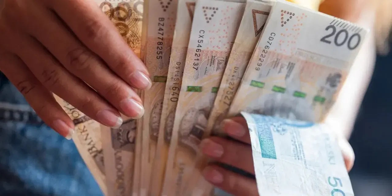 Dłonie trzymają plik banknotów 200 zł i 50 zł. Jak egzekwować obowiązek naprawienia szkody, gdy sprawca nie chce zapłacić?