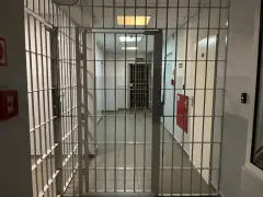 Korytarz więzienny z kratami, gdzie każdy krok może prowadzić do spotkania z niebezpiecznym więźniem.