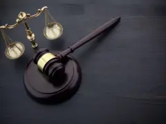Młotek sędziowski i waga sprawiedliwości na ciemnym tle. Symbolizują sprawiedliwość i prawo, a także mogą oznaczać zmianę miejsca wykonywania prac społecznych.