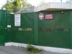 Zielona brama z drutem kolczastym i znakiem "Schronisko dla Nieletnich w Dominowie". To miejsce, gdzie młodzież potrzebuje wsparcia, a nie kary.