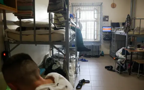 Wnętrze celi, areszt śledczy. Dwie osoby na łóżkach piętrowych, okno z kratami, telewizor.