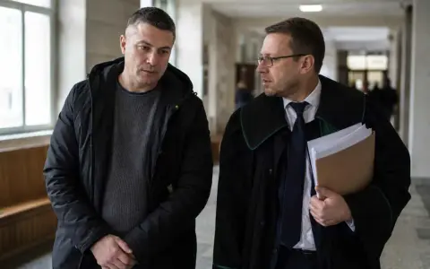 Mężczyzna w czarnej kurtce rozmawia z prawnikiem w todze. Czy usłyszą wyrok w zawieszeniu?